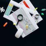 Overhead view of an office desk with financial documents, a magnifying glass, and stationery items, suggesting business analysis.