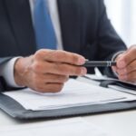 Businessman in suit holding pen, ready to sign documents. Close-up detail shot.